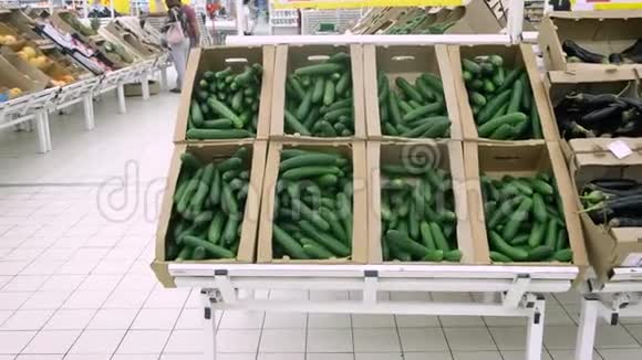 女孩选择并在超市买黄瓜盒子里的一大堆黄瓜视频的预览图