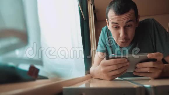 男人在智能手机上玩网络游戏强烈的情绪愤怒的男人坐在窗边的火车上的生活方式慢慢慢慢视频的预览图