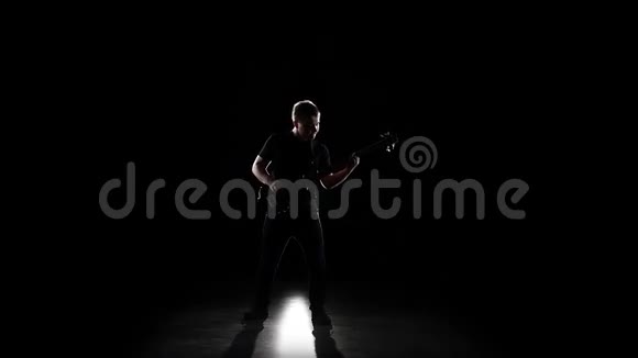 低音吉他手在膝盖上演奏一首曲子慢动作视频的预览图