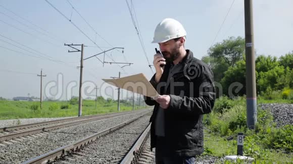 铁路交通检查员在对讲机上烦躁地交谈戴着蓝图计划的白盔铁路工人视频的预览图