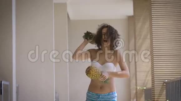 酒店走廊穿着白色泳衣和蓝色裤子的女孩免费在她的两个菠萝的手中Brunette视频的预览图