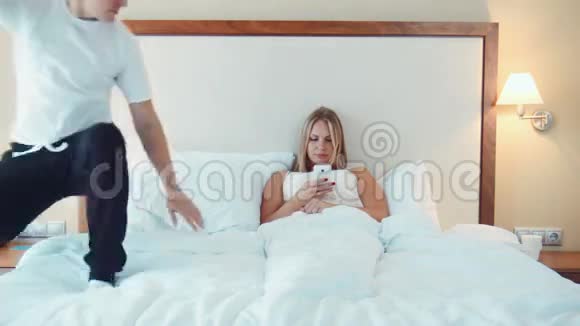 笑男人在床上和女人用电话视频的预览图