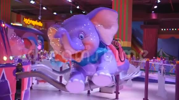 吸引孩子小女孩骑着小象旋转木马在商场中心的游戏公园视频的预览图