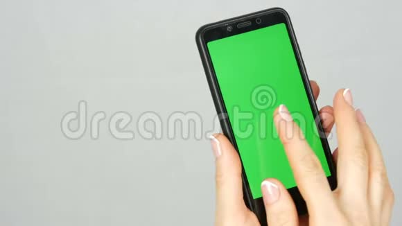 整洁干净的女性双手漂亮的指甲手里拿着一部黑色智能手机上面有绿色屏幕或铬键视频的预览图