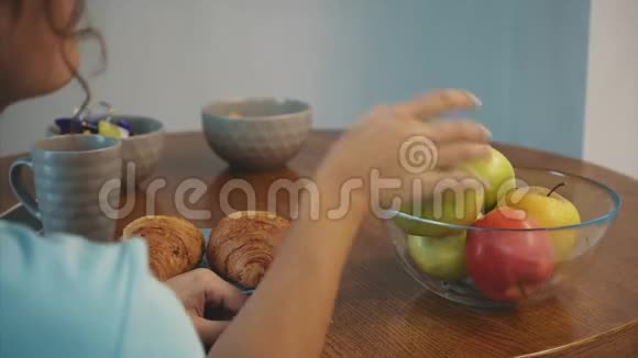 美丽的年轻苗条的黑发一只手拿着绿苹果另一只手拿着牛角面包视频的预览图