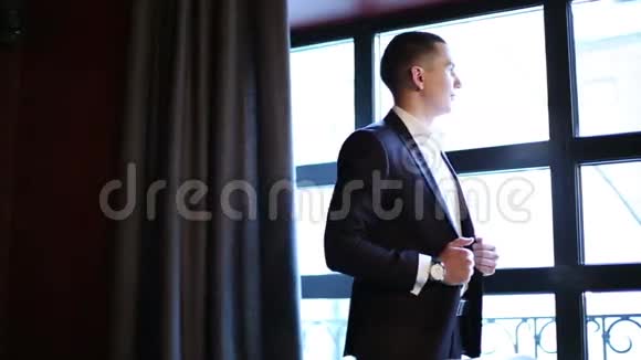 穿着经典西装的年轻商人站在窗前视频的预览图