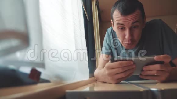男人在智能手机上玩网络游戏强烈的情绪愤怒的男人坐在窗边的火车上生活方式缓慢视频的预览图