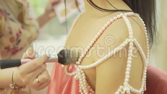 专业女性化妆师在美容院将荧光笔涂在漂亮的模型锁骨肩皮上视频的预览图