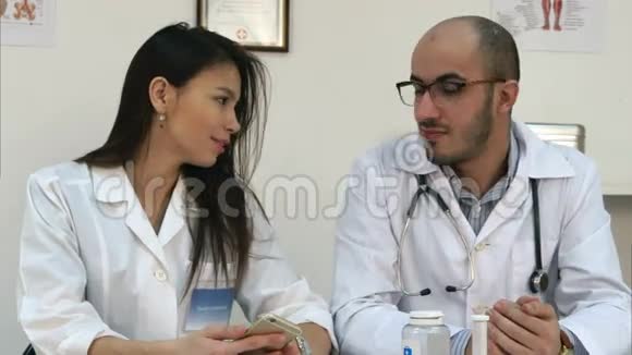 年轻的医生和漂亮的护士在他们的办公桌上打电话自拍视频的预览图