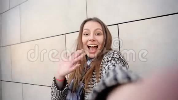 一位美丽快乐的旅游妇女拿着摄像机在一张照片上拍摄自己的自拍照片视频的预览图