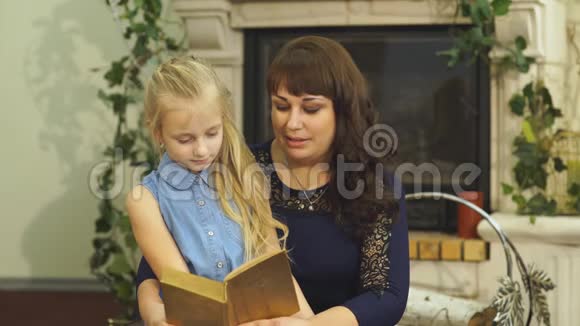 妈妈和心爱的小女儿坐在椅子上读童话视频的预览图