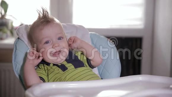 可爱害羞的婴儿在婴儿椅上笑着看着镜头视频的预览图