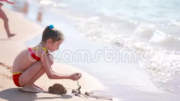沙滩上玩沙子的小女孩在海里的孩子儿童海滩视频的预览图