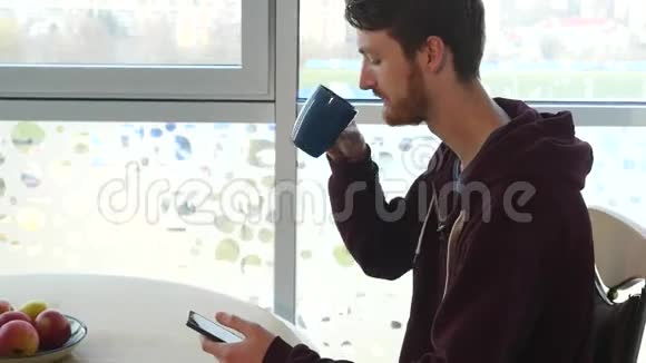 年轻人用智能手机在厨房里一桌一桌地喝咖啡视频的预览图
