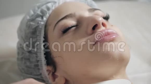用刮刀泡沫从面部取出年轻漂亮的女人在美容院接受治疗面部清洁泡沫视频的预览图