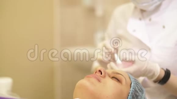特写美容师在治疗和按摩后用手在病人脸上涂抹面霜美容程序的概念视频的预览图