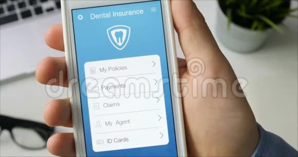 用坐在办公桌前的智能手机应用支付牙科保险视频的预览图