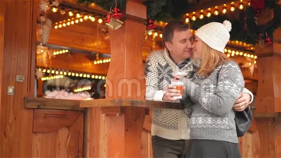 快乐的年轻夫妇在圣诞市场上尽情享受欢乐和亲吻美丽的家庭一起欢笑一起喝酒视频的预览图