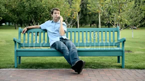 坐在长凳上讲手机的青少年视频的预览图