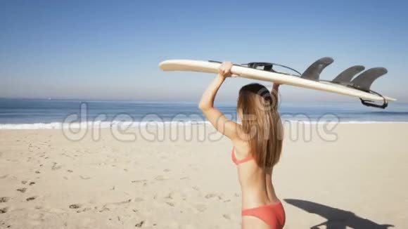 年轻女子在海滩上拿着冲浪板视频的预览图