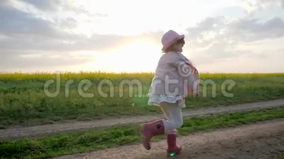 微笑的女孩子小女孩沿着田间的道路奔跑奔跑的孩子快乐的孩子在城外玩耍健康的孩子视频的预览图