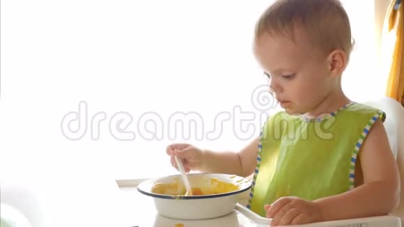 一个小男孩坐在椅子上在白色背景下独自吃粥视频的预览图