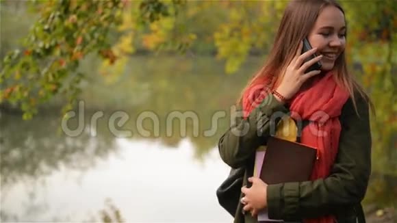 秋天漂亮的学生女孩在手机上聊天秋高气爽的高加索女人在智能手机上交谈视频的预览图