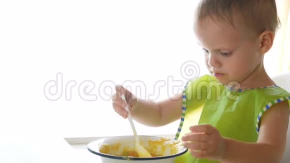 一个小男孩坐在椅子上在白色背景下独自吃粥视频的预览图