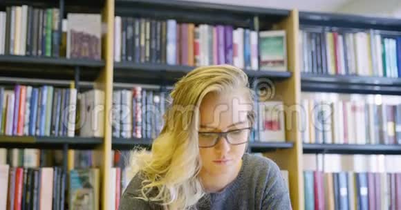 在学校图书馆工作的戴眼镜的女学生视频的预览图