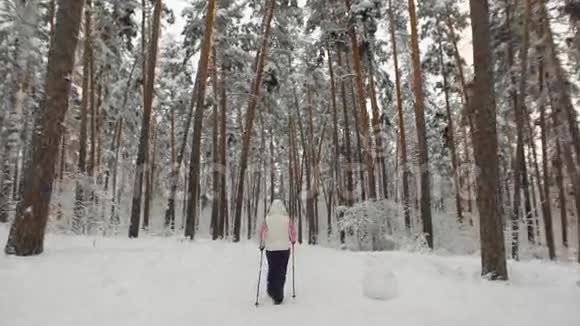 在树林里的雪道上行走的一位老年妇女的后景现代体育形式视频的预览图