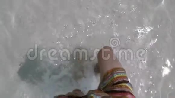 在海滩上清澈的海水中行走的男子双脚特写镜头在度假期间在海边缓慢行走的动作镜头视频的预览图