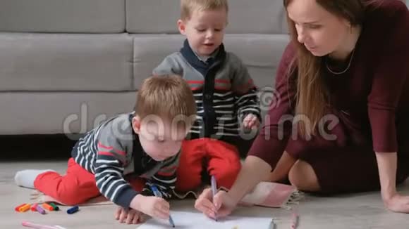 家人妈妈和两个双胞胎兄弟一起画记号摸着笔坐在地板上视频的预览图
