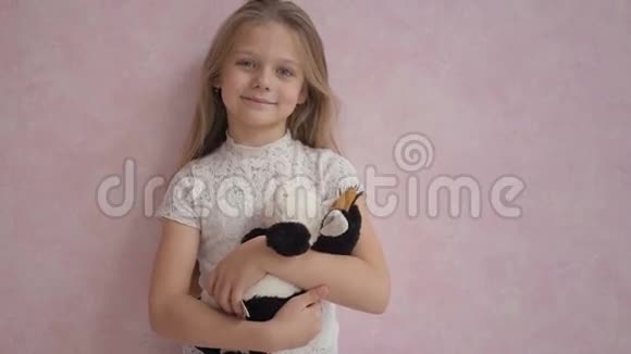 可爱的小女孩穿着休闲装手里拿着柔软的玩具对着相机微笑视频的预览图