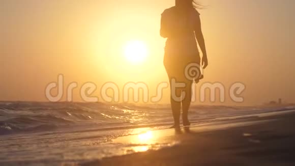 浪漫的女人光着脚在海滩上散步在日落时在海里缓慢地运动1920x1080视频的预览图