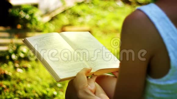 在阳光明媚的一天一位迷人的年轻女子在户外看书视频的预览图