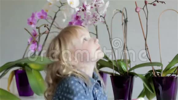 一个穿着蓝色连衣裙的小漂亮女孩正在纠正她的金发卷发视频的预览图