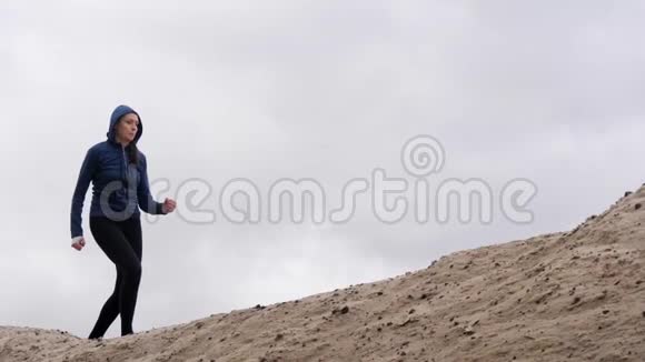 身材苗条的妇女慢跑者在沙漠中跑步黑暗风暴云在背景视频的预览图