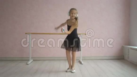 戴着耳机听智能手机音乐跳舞的快乐小女孩视频的预览图