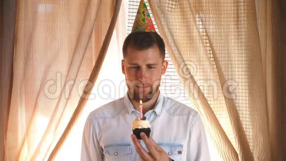 一个戴着派对帽的人在蛋糕上吹蜡烛视频的预览图