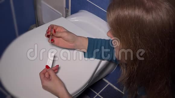 女人在壁橱盖子上用吸管做妊娠试验等待结果视频的预览图