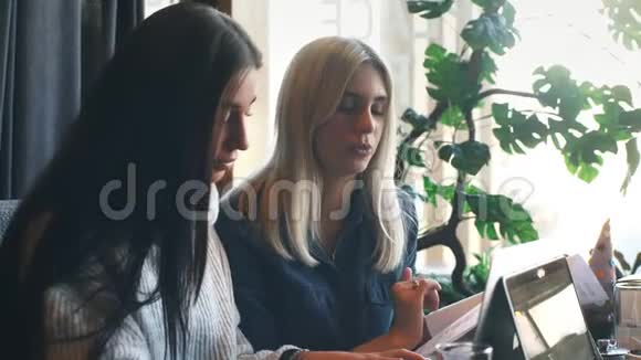 两个女商人正在咖啡馆里积极地用笔记本电脑工作并讨论这项工作视频的预览图