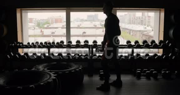 运动员的剪影与哑铃健身室黑色背景男子与哑铃健身视频的预览图