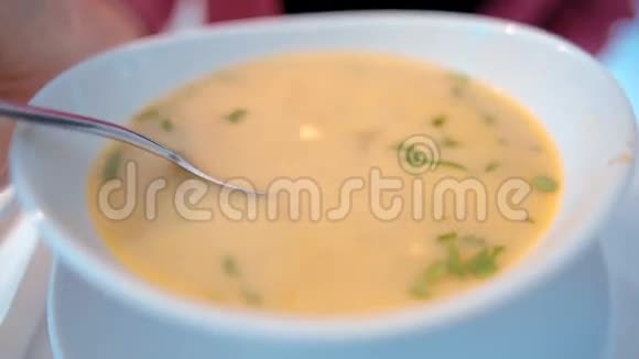 带有一个大勺子的人吃一个白色盘子里美味的黄汤视频的预览图