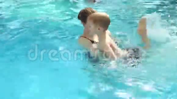 一个年轻的女人在度假时教一个孩子在游泳池里游泳视频的预览图