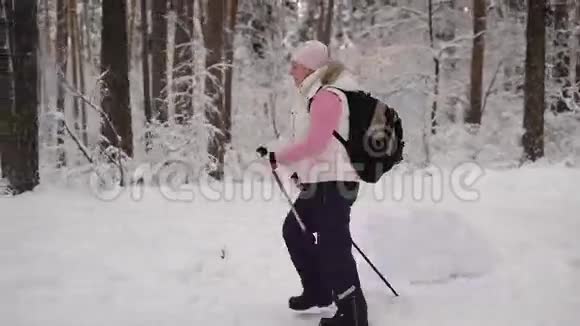 户外活动妇女在冬季自然中用滑雪杆进行北欧行走的侧视退休女士在野餐视频的预览图