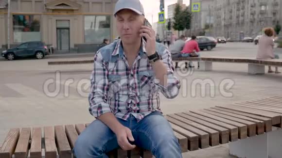 白种人坐在城市广场的长凳上打电话视频的预览图