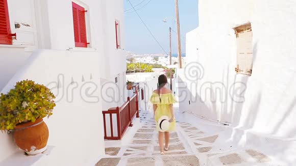 美丽的女人在户外的老街和Mykonos典型的希腊传统村庄有白色墙壁的街道上的女孩视频的预览图
