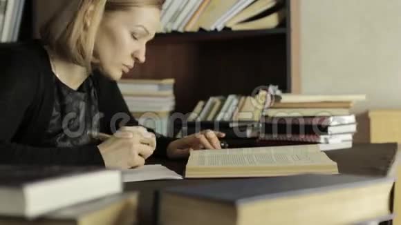 重点学生在大学图书馆学习坐在书桌前做作业的女学生视频的预览图
