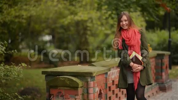 学生女孩拿着书穿着背包户外微笑快乐地在公园里散步高加索女子大学或视频的预览图