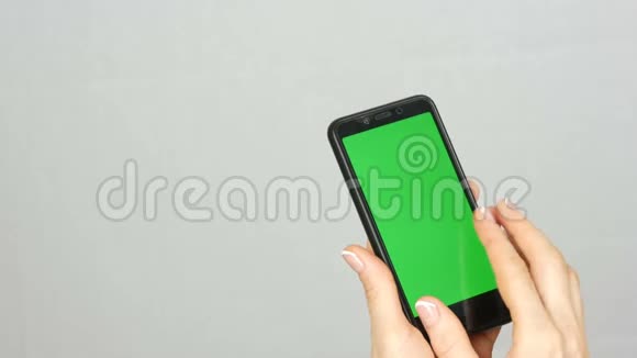整洁干净的女性双手漂亮的指甲手里拿着一部黑色智能手机上面有绿色屏幕或铬键视频的预览图